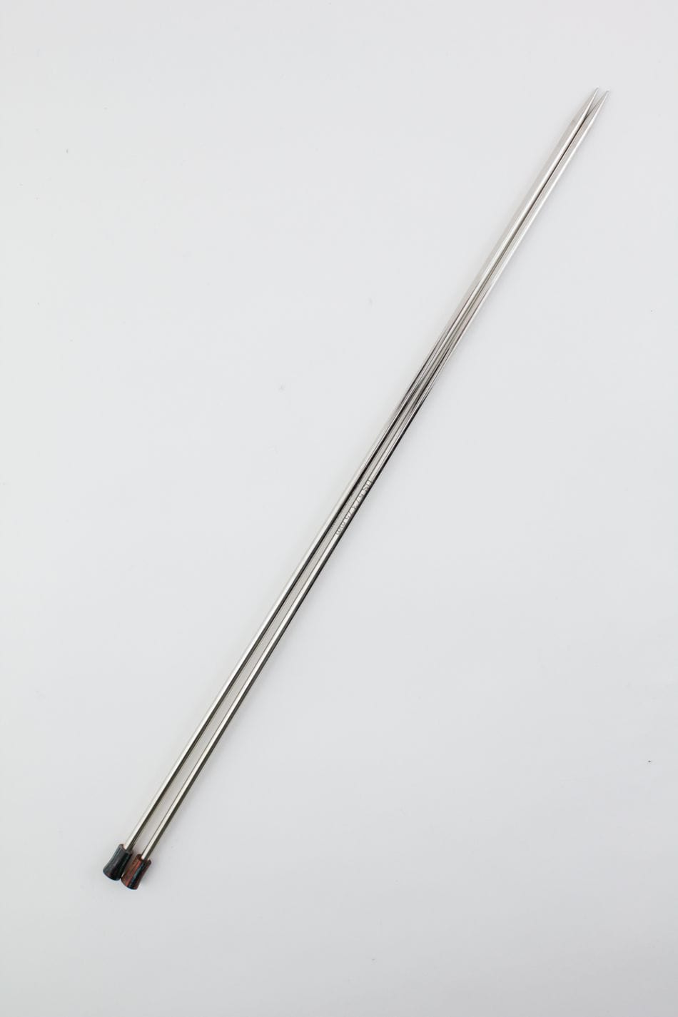 A pair of Knit Pro Nova Metal Single Point Knitting Needles, 10" or 14", by Accessories Unlimited, shown diagonally on a white background with red and black stoppers at the ends.