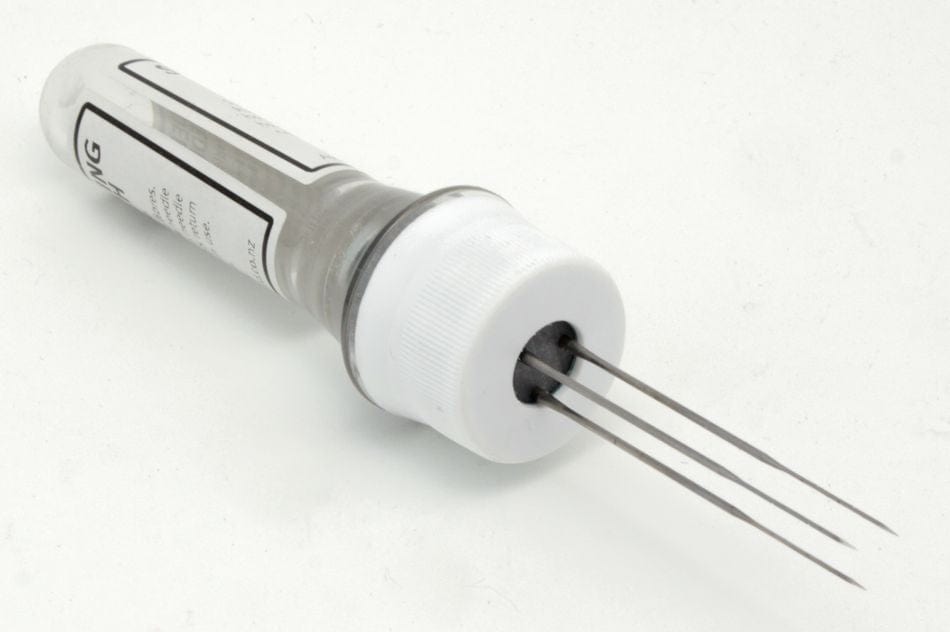 The Ashford Needle Felting Punch Tool by Ashford Handicrafts Limited is a plastic container with a white cap, holding three long, thin felting needles arranged parallel and protruding from the cap.