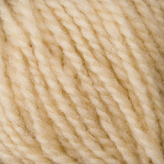 Close-up of Bartlettyarns' Bartlett Maine Wool Sport Weight Cones, featuring cream-colored yarn with a homespun look. The yarn's tightly spun fibers reveal visible texture and twists, offering a plump and cozy feel ideal for sport weight projects.