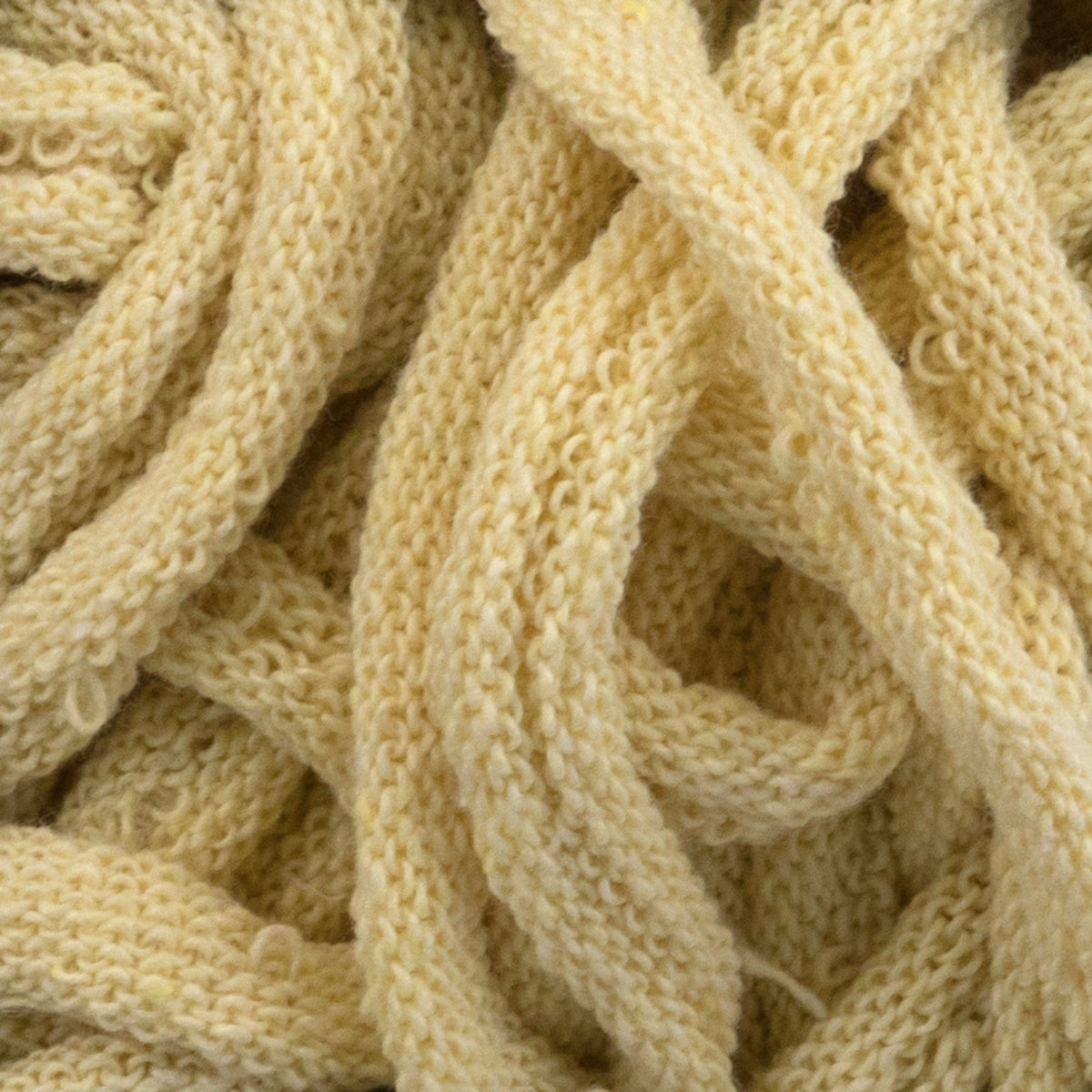 A close-up view of Harrisville Potholder Loops - Traditional Size by Friendly Loom reveals tangled cream-colored threads forming a chaotic yet cozy pattern similar to a traditional loom. The texture is soft and slightly fuzzy, resembling wool or cotton loops, with intertwined strands creating an intricate appearance.