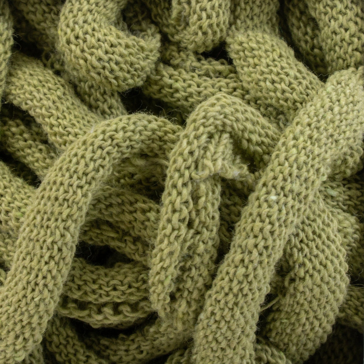 Close-up of a textured, intertwined green fabric made from Harrisville Potholder Loops - Traditional Size by Friendly Loom, showcasing intricate cotton loops and braids. The yarn appears soft and thick, akin to what you might find on a traditional loom, creating a cozy and tangled appearance.