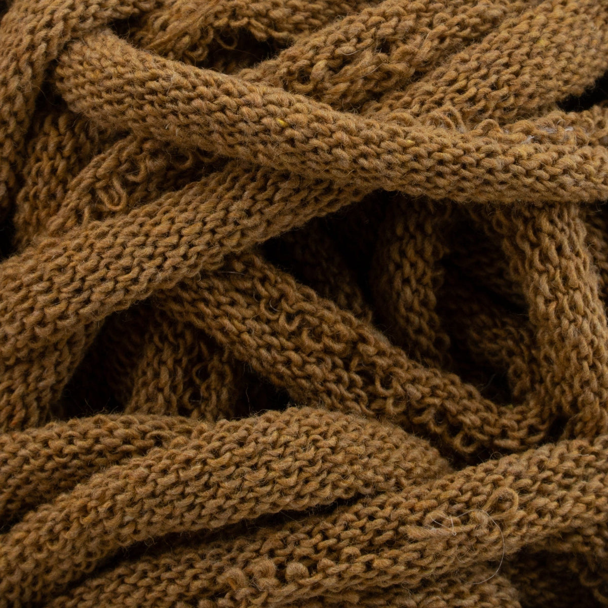Close-up of a pile of thick, brown Harrisville Potholder Loops from Friendly Loom, intertwined like cotton loops on a traditional loom, creating a textured, cozy pattern.