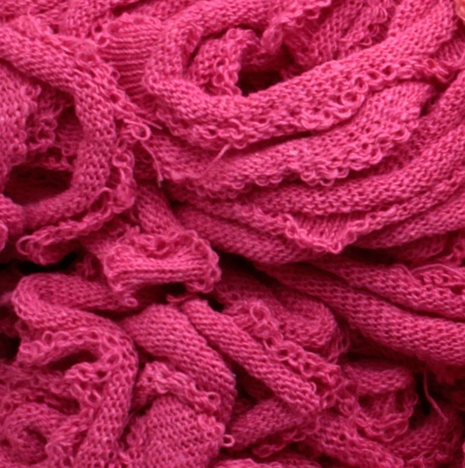 A close-up of a tangled pile of Harrisville Potholder Loops - Traditional Size in a bright pink hue, from Friendly Loom, resembling the intricate weave you'd find on a traditional loom, showcasing its wavy texture and soft, fibrous appearance.