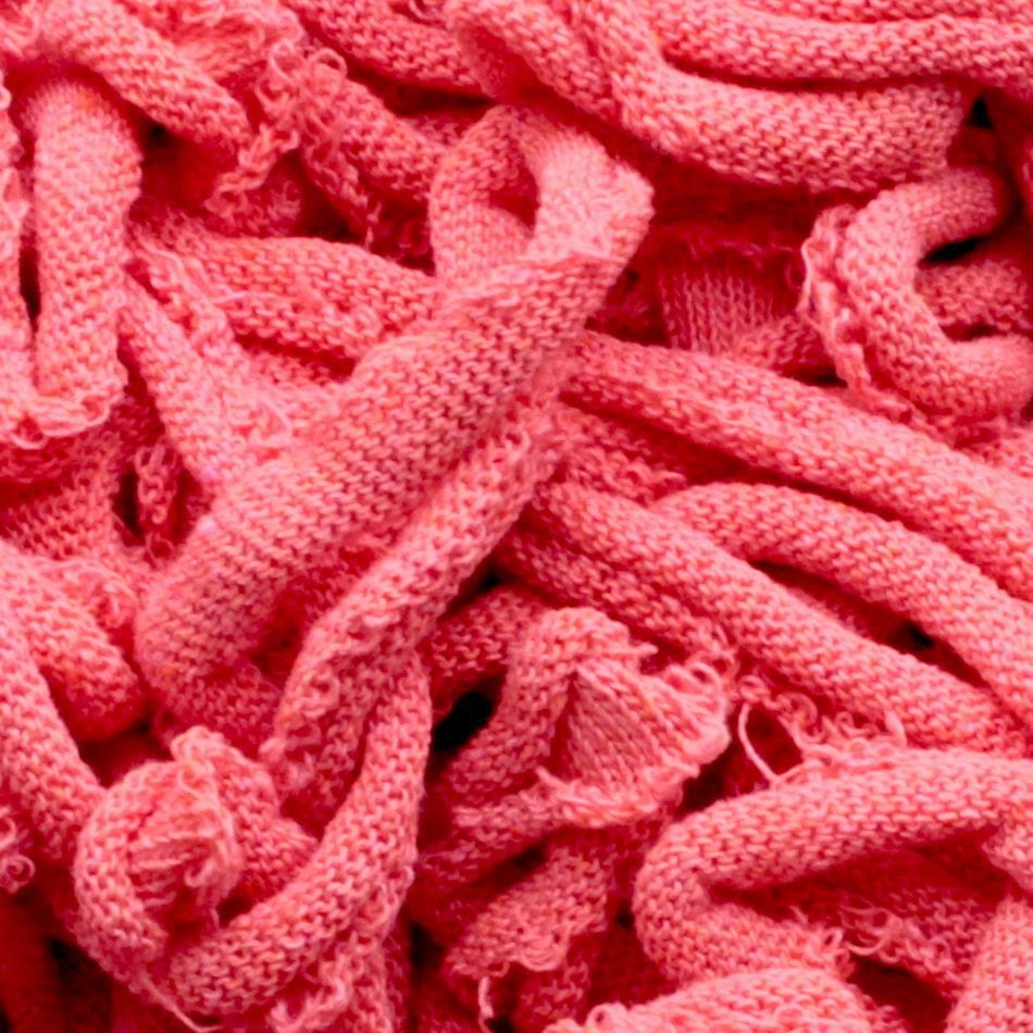 Close-up of a pile of tangled, pink Harrisville Potholder Loops by Friendly Loom, creating a textured and chaotic pattern reminiscent of traditional potholder looms.